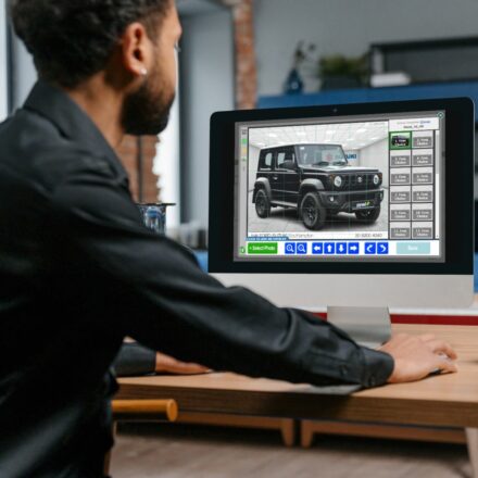 man in marketing department at dealer using pyxel editing suite to adjust car photograph